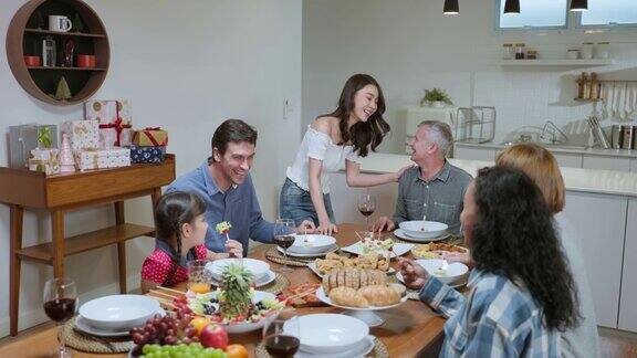 多民族大家庭共进晚餐在家里享受晚会有吸引力的一群不同的人在家里的餐桌上欢聚一堂吃着美食庆祝周末团聚