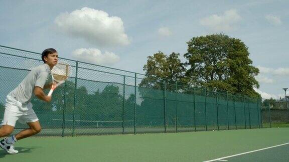 一个打网球的年轻人从底线打出了一个漂亮的球然后庆祝