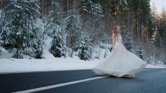 新娘穿着婚纱在柏油路上走着跑着跳着在冬天的雪林里