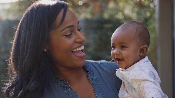 微笑的非洲裔美国母亲在花园里拥抱和玩耍的女儿的肖像