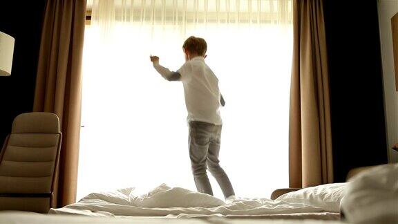 活泼时尚的男孩早上在床上蹦蹦跳跳