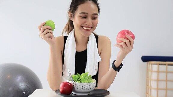 美丽的亚洲女人健康的博主展示了苹果水果和干净的减肥食品在摄像机前录制在家的视频直播在线社交媒体上的健身影响者