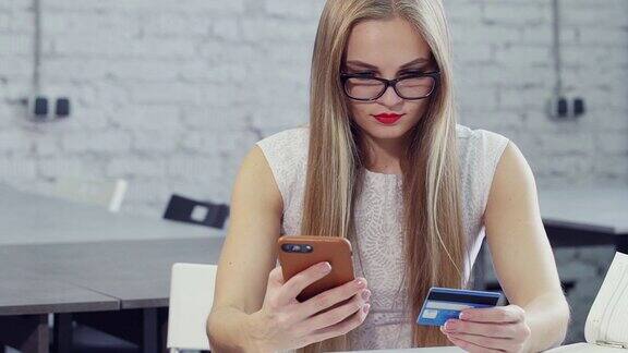 女商人在办公室用信用卡和智能手机在网上购物付款