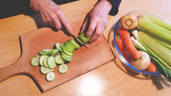 一名妇女在厨房板上用手切黄瓜