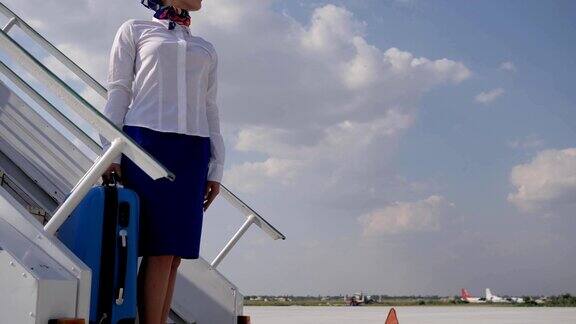 在机场漂亮的空中小姐在飞机的楼梯上提着手提箱