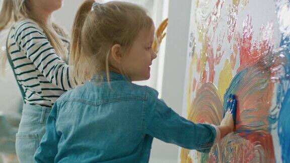 两个快乐的小女孩用彩色颜料蘸手在墙上画手印和抽象画他们开心地笑着房屋正在装修