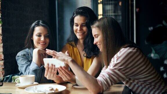 快乐的女孩看着智能手机屏幕滑动微笑着在咖啡馆享受乐趣