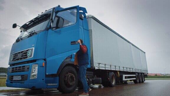 卡车司机穿过公路在农村地区进入他的蓝色长途半卡车与货物拖车连接跨国家和大陆运输货物的物流公司