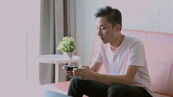 年轻的亚洲男子在智能手机上玩电子游戏