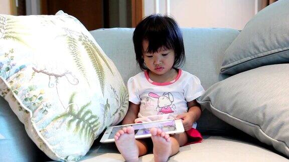 一个亚洲小女孩在客厅玩无线平板电脑高清