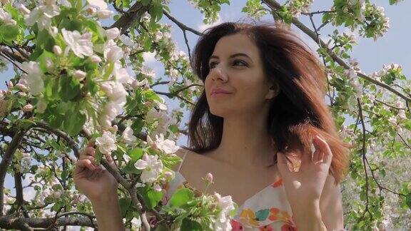 一个年轻漂亮的白人女人站在一个盛开的苹果园的肖像