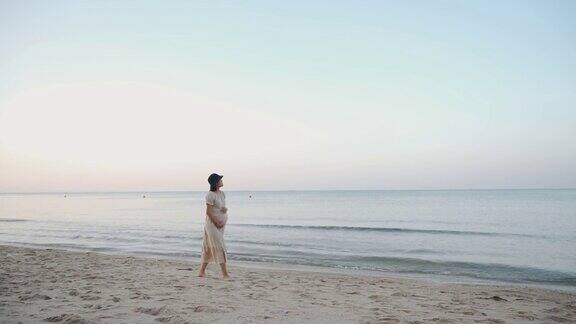 亚洲孕妇走在沙滩上