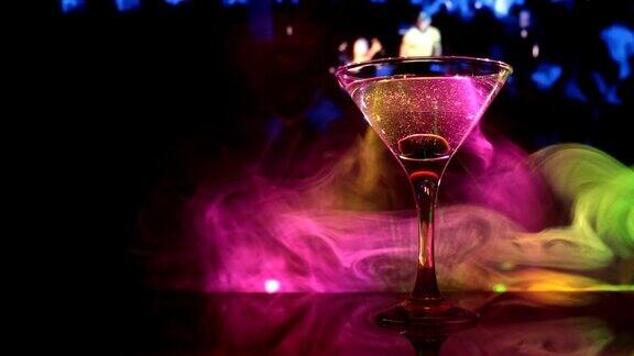 滑块杯中有橄榄的马提尼近距离观看与俱乐部的酒在黑暗的雾色调的背景有选择性的重点酒精饮料倒入马提尼杯的瓶子俱乐部饮料