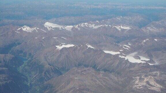 在夏季飞越欧洲阿尔卑斯山冰川的景观从飞机窗口鸟瞰图