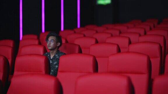 亚洲华人少年在电影院看电影脸上毫无表情