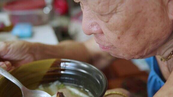 年长的亚洲女人在家吃饭