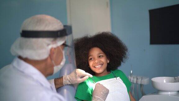 牙医坐在牙医椅上检查孩子的牙齿