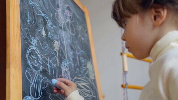 小女孩用粉笔在黑板上画画