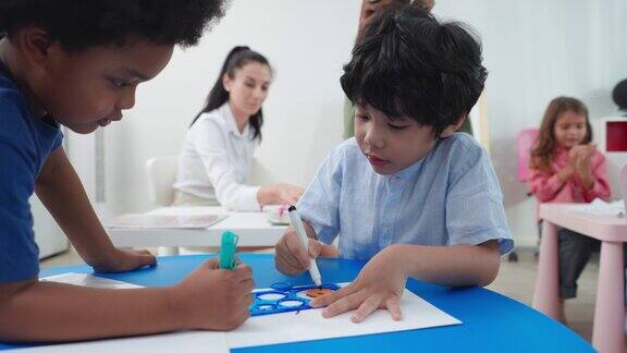 美术课上两名小学生在白纸上画画