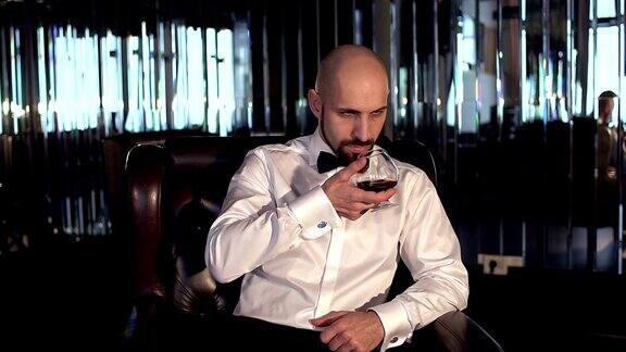 优雅的男人坐在餐厅里喝着白兰地