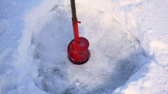 冰钻洞的特写在冰上为冬季捕鱼和铲清理雪