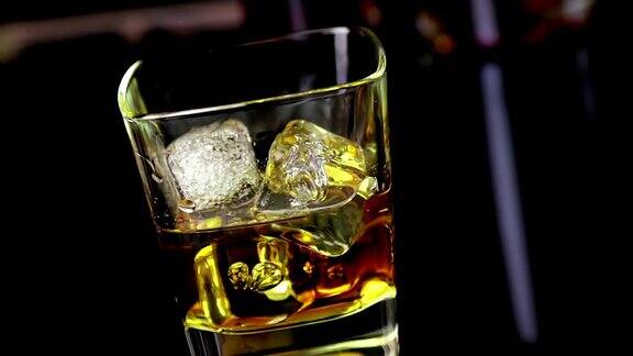 酒吧间招待员将威士忌和冰块倒入木桌上的玻璃杯中观景