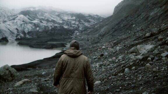 年轻男子独自走在冰湖上的背影在冰岛冰川附近的火山中徒步旅行的男性