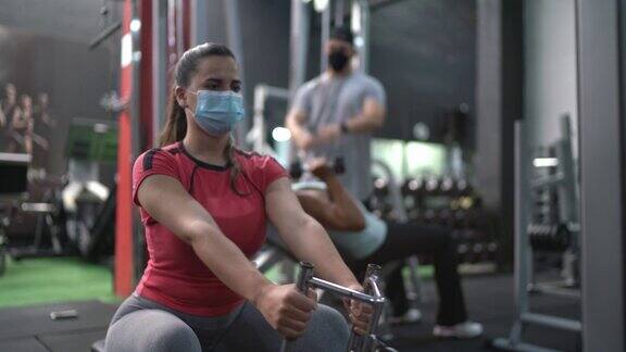 年轻女子在健身房训练戴着口罩