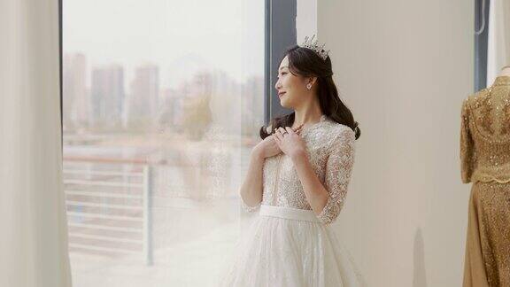 一位身着婚纱的年轻女子站在落地窗前