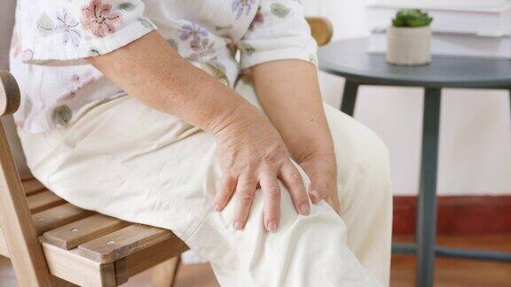 特写亚洲老年妇女感到疼痛疼痛膝盖受伤时站在家里和坐在家里骨关节炎