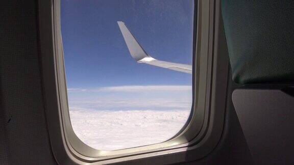 透过飞机窗口观看飞机机翼在云层之上