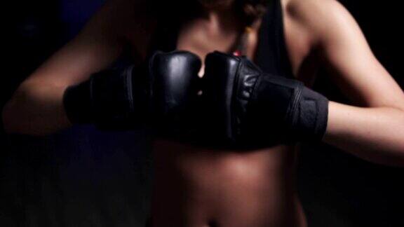 一个女人在暗室里踢着戴着拳击手套的手准备训练Slowmotion拍摄
