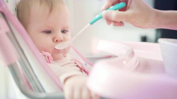 婴儿吃婴儿食品妈妈用勺子用手喂宝宝