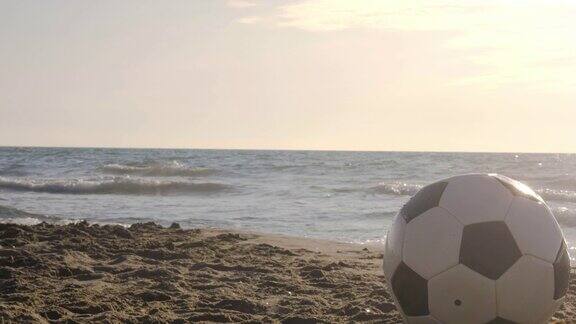 经典的黑白足球在日落时分被海浪带到海边的水里