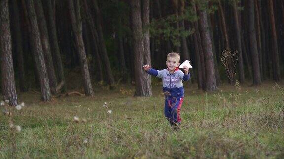 一个小男孩玩玩具飞机在公园里跑步自由梦想