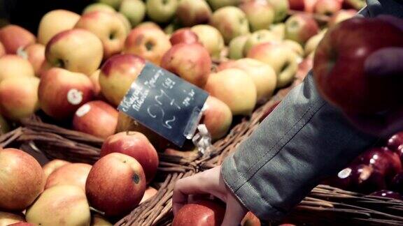 年轻女子在超市挑选水果在杂货店挑选新鲜红苹果的女人特写镜头