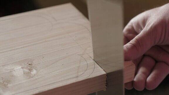 木匠用手锯从一块松木板上锯下一块木头手工木工工具在工作木工艺术