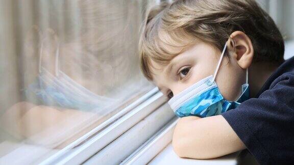 这个悲伤、忧郁的小男孩戴着一个保护面罩从学校的窗户往外看