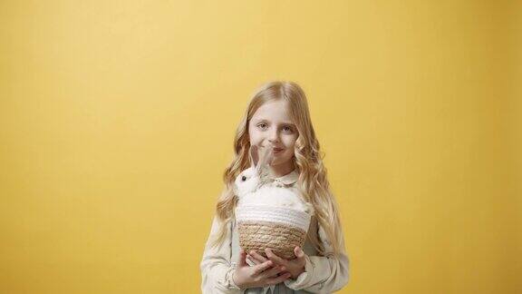 小女孩戴着兔子耳朵微笑手里拿着一只兔子的篮子