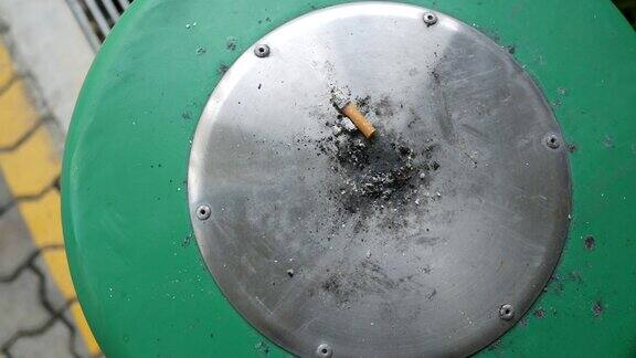 把桌上烟灰缸里正在燃烧的香烟合上