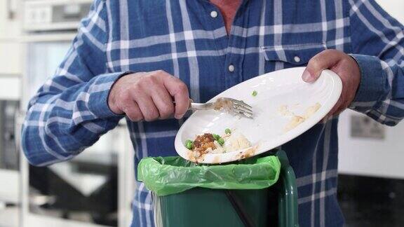 一名男子将残羹剩饭扔进垃圾桶