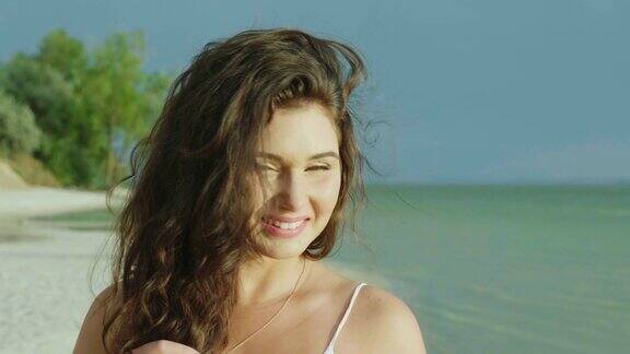 热带海滩上一位年轻女子的肖像看着镜头微笑着4K慢动作视频