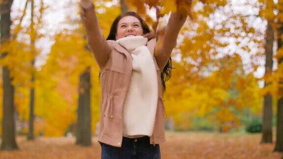快乐的女人在秋天的公园里玩树叶
