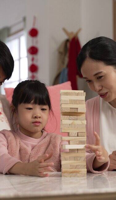 垂直屏幕:快乐的亚洲父母在家里一起过中国农历新年时拍着手称赞他们的女儿做了一件好砖文上门翻译:春