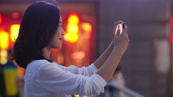 年轻的亚洲女子用手机拍摄城市4k