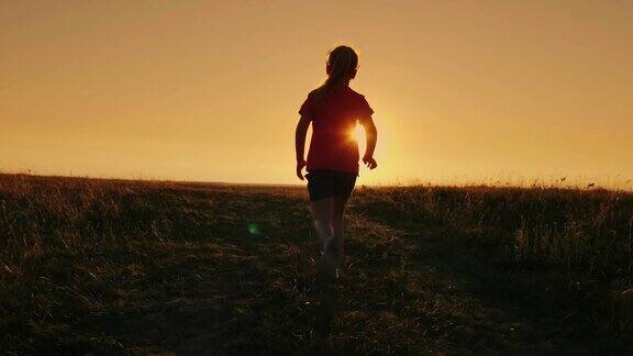 无忧无虑的女孩跑上了山在夕阳的背景克服困难首先取得成就