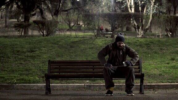 饥饿的无家可归者晚上坐在长凳上数钱