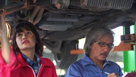 高级技师男子培训班为年轻技师妇女检查汽车发动机在车库