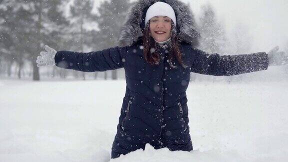 快乐的女人坐在雪堆里在冬季公园里愉快地散步