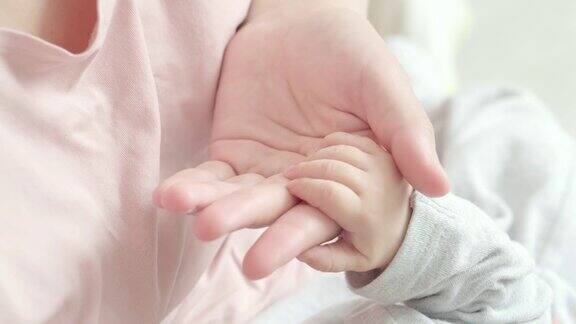 4k新生婴儿牵着妈妈的手妈妈抚摸着宝宝的小手让宝宝感受到她的爱温暖和安全母性、家庭、生育观念